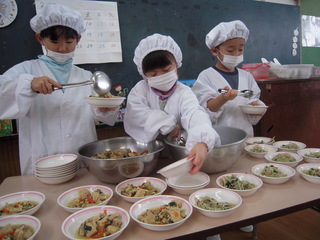 給食当番が給食を盛り付けている写真